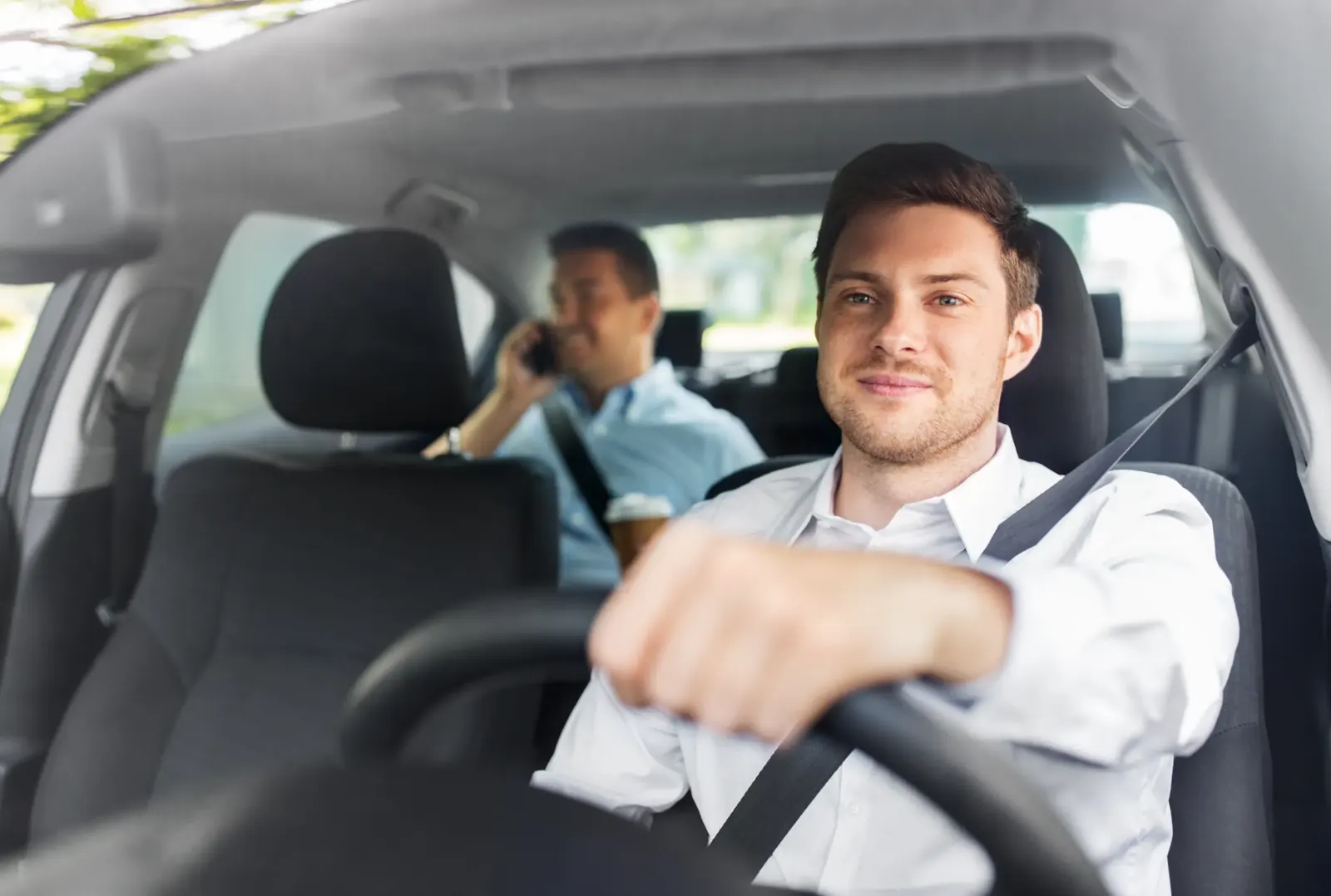 Driver and rear passenger travelling in a car, both wearing seat belts