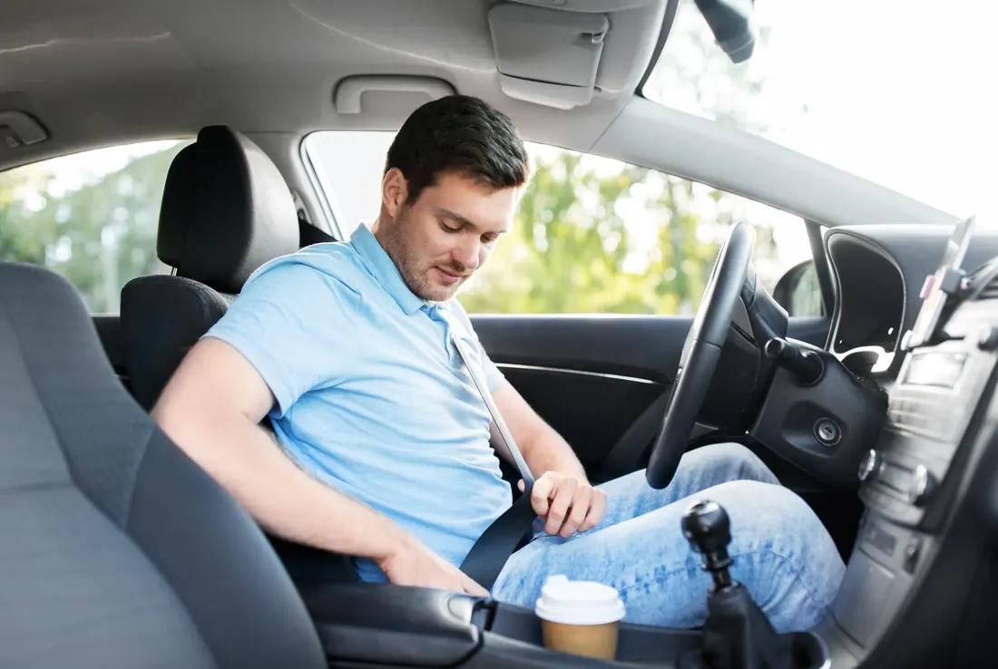 Driver fastening the seat belt before setting off