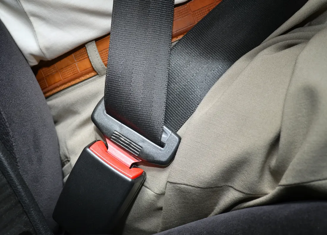 Lap section of a fastened seat belt running low across an occupant