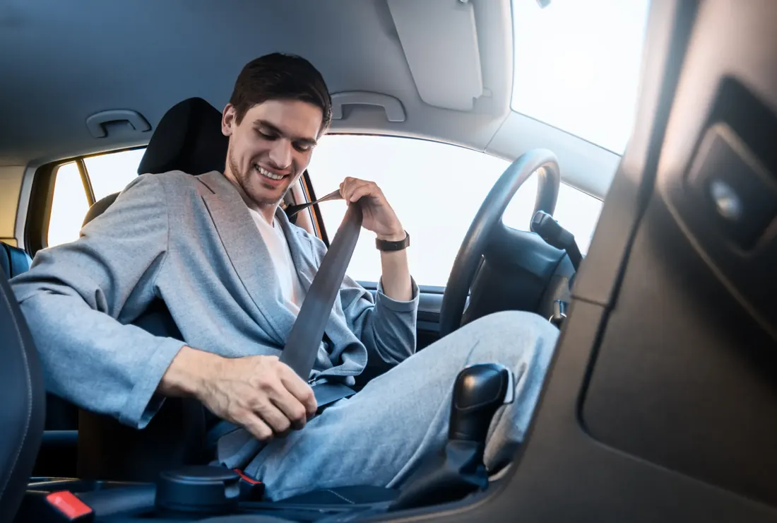 Occupant drawing seat belt webbing out across the body inside a car
