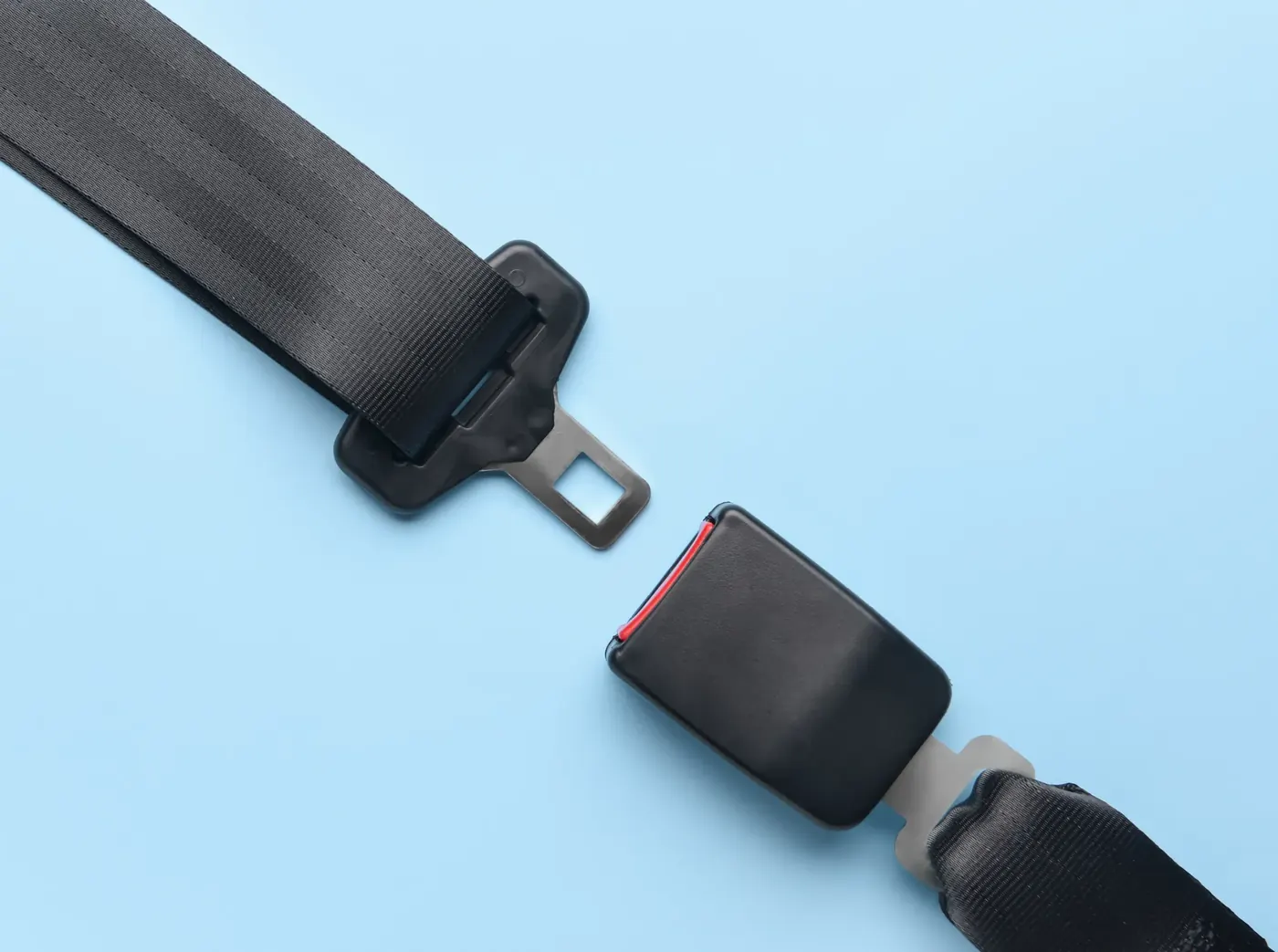 Two halves of a seat belt assembly laid flat showing latch plate and buckle