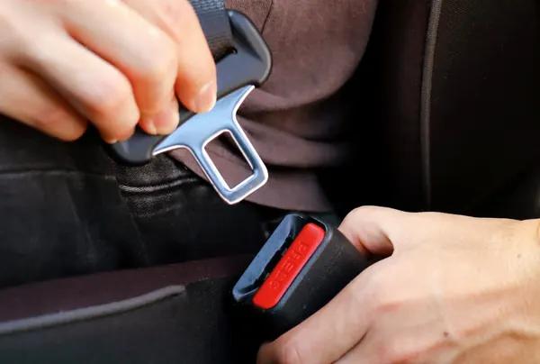 Hands engaging a latch plate into a buckle